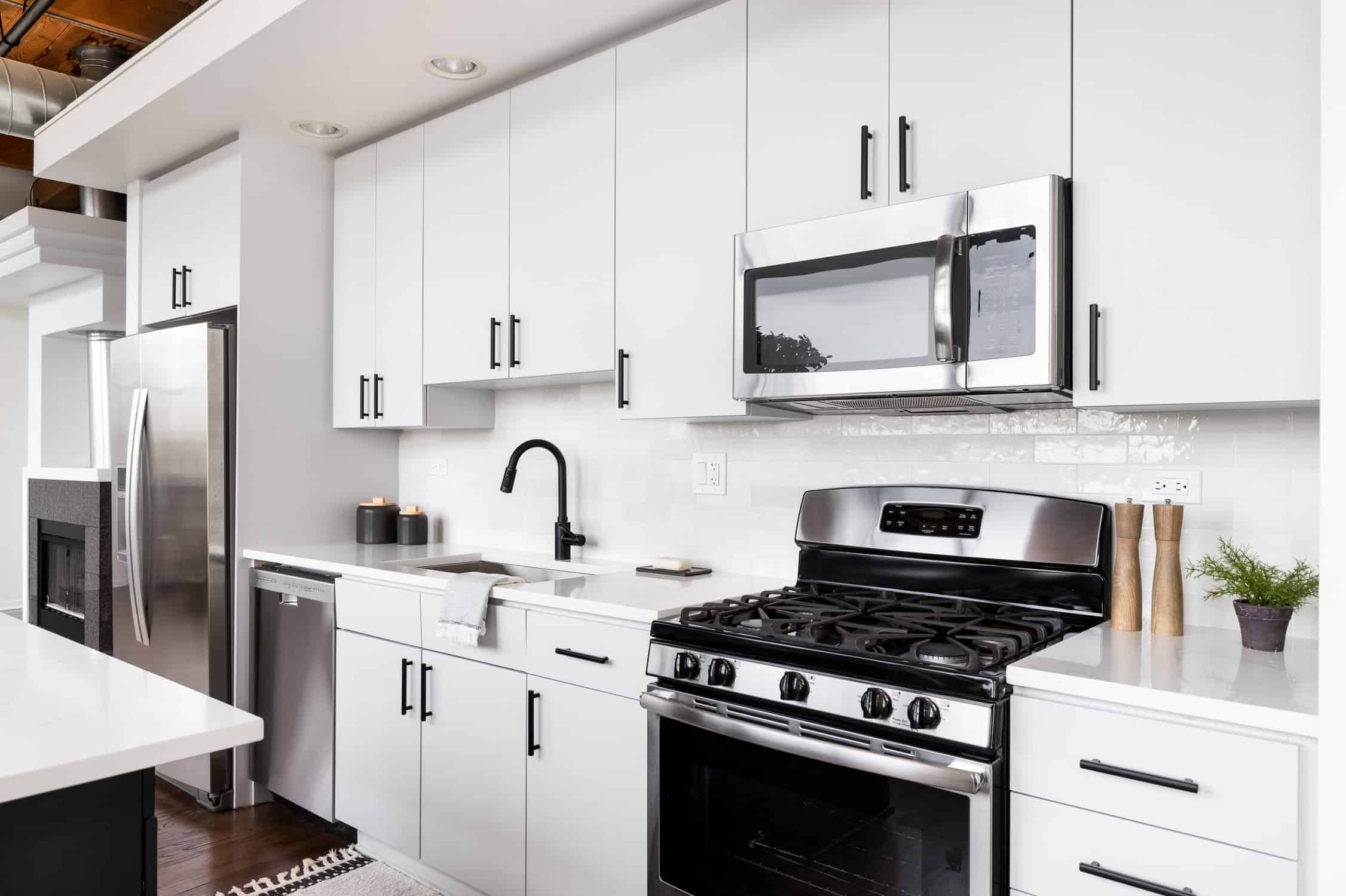 A white kitchen with stainless steel appliances. cabinet painting vs replacement