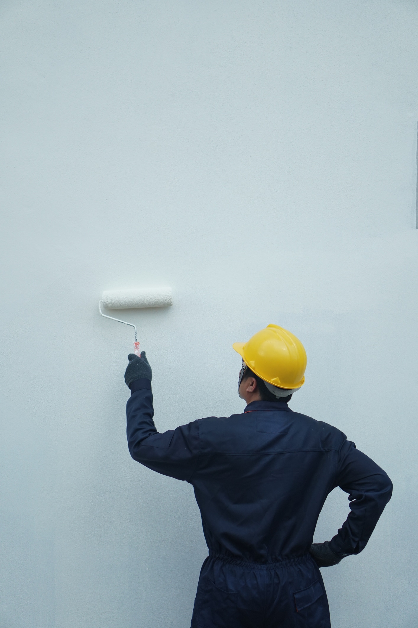 Behind the painter is painting a house wall with a roller, there is space for text.