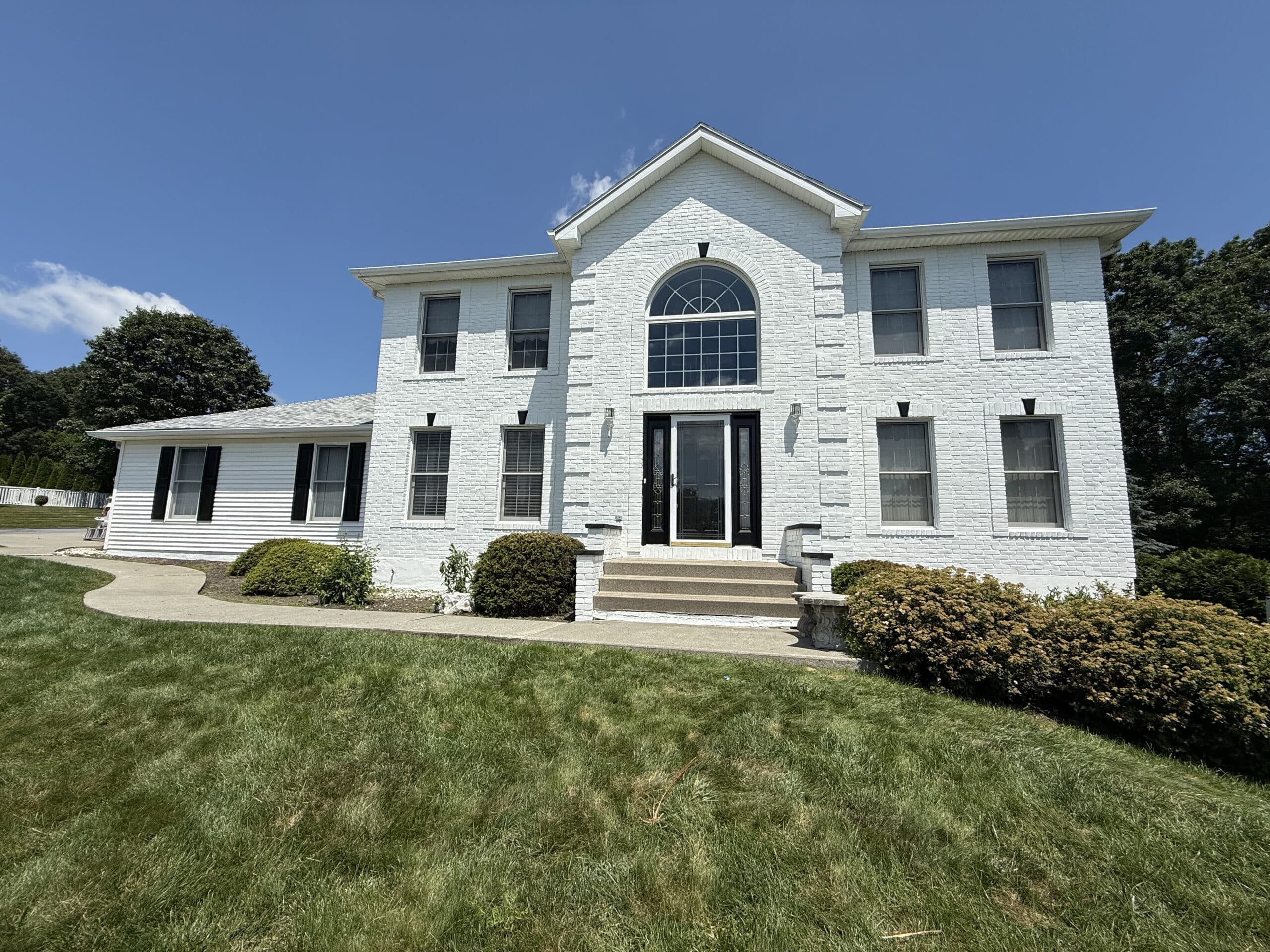 Professional Exterior House Painting Service A newly painted dark gray house with black trim and garage doors, surrounded by autumn trees.